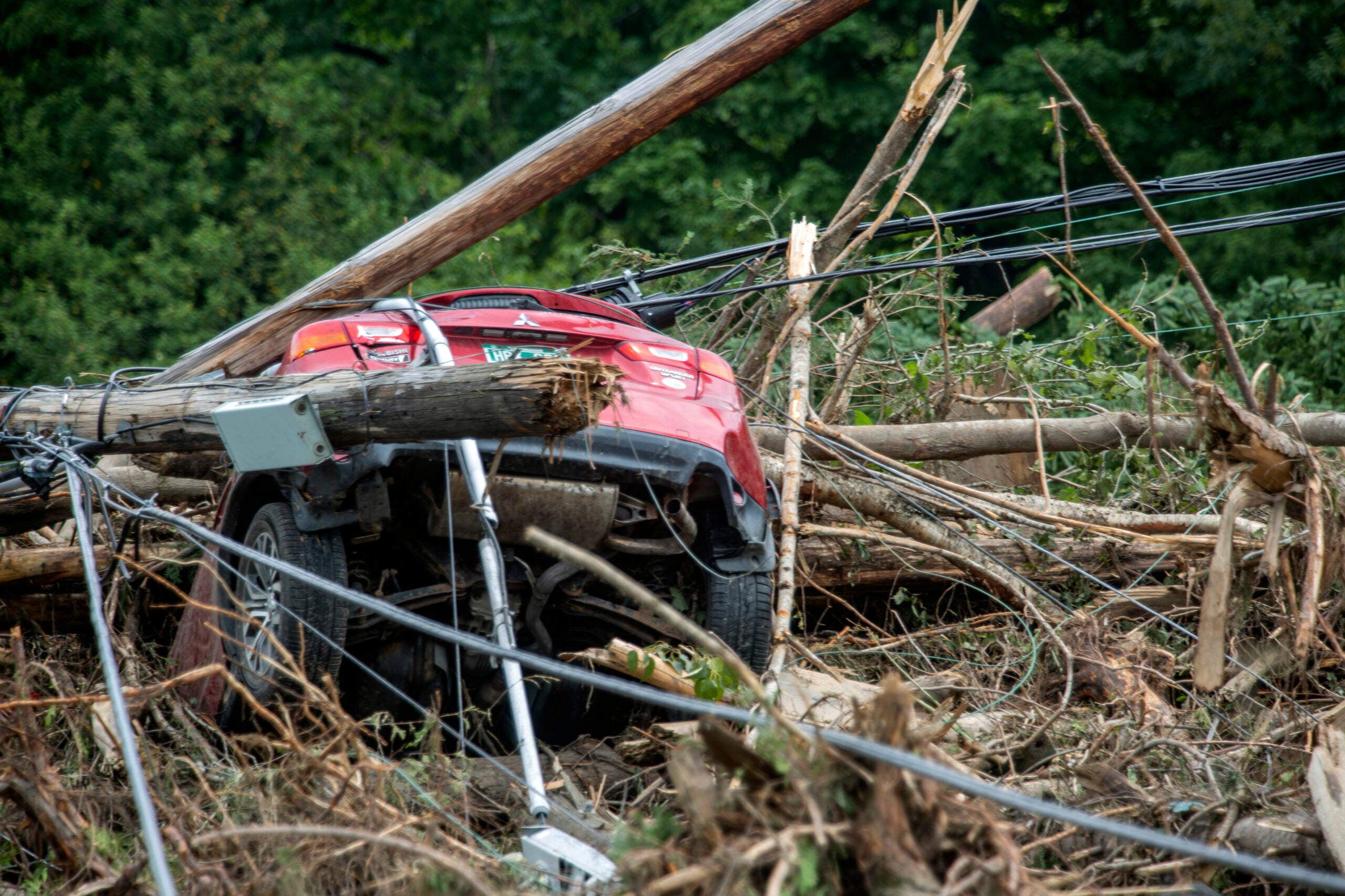 A damaged car sits amid flood debris in Lyndon, Vt.
