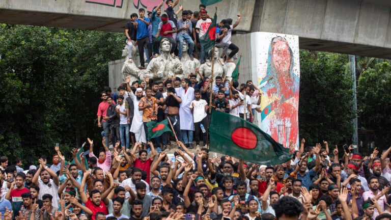 Protesters climb a public monument as they celebrate the news of Prime Minister Sheikh Hasina's resignation, in Dhaka, Bangladesh, Monday, Aug. 5, 2024.